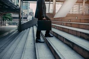 gros plan des jambes d'un homme d'affaires marche avec sa mallette dans l'escalier de la ville moderne, croissance de l'entreprise, succès, grandir. notion d'entreprise. photo