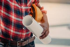 gros plan d'ingénierie tenant un casque de sécurité et un plan. photo