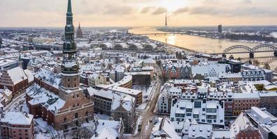 photo vue aérienne du drone volant panoramique à st. l'église saint-pierre et la vieille ville de riga en arrière-plan de la rivière daugava et du centre-ville par un beau matin d'hiver.