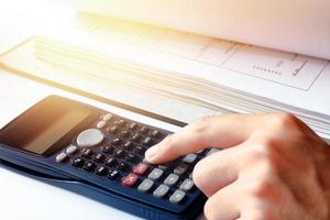 homme de main faisant des finances avec une calculatrice au bureau à domicile. photo