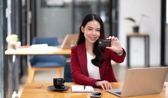 jeune femme d'affaires asiatique aime faire du shopping en ligne par carte de crédit. regardant la caméra. photo