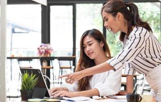 deux jeunes belles femmes d'affaires asiatiques dans la conversation, échangeant des idées au travail. photo