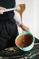 gros plan - confiseur - femme remue le chocolat pour faire des chocolats faits maison photo