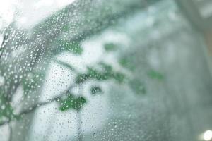 mise au point sélective, gouttelettes d'eau sur le verre un jour de pluie. gouttes de pluie pendant la pluie en jour de pluie à l'extérieur du verre de la fenêtre avec un arrière-plan flou. photo