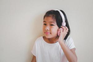 portrait de jeune fille asiatique heureuse appréciant la musique avec des écouteurs sur fond blanc. profitez du concept sonore. photo