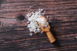 fleur de sel, est un sel qui se forme comme une fine croûte délicate à la surface de l'eau de mer dans la cuillère en bois sur fond de bois. photo