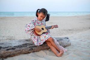 jeune fille asiatique jouant du ukulélé sur la plage. photo