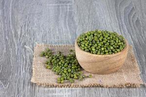 les haricots verts débordent de bols en bois et s'empilent sur le sac tissé photo