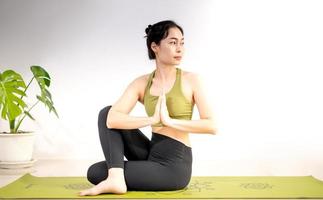 femme faisant du yoga sur le tapis de yoga vert pour méditer et faire de l'exercice à la maison. photo