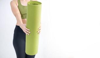 main féminine tenant un tapis de yoga vert pour préparer l'exercice sur le tapis. photo