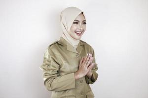 travailleur civil musulman portant l'uniforme marron et le hijab saluant d'un geste de la main et souriant à la caméra photo