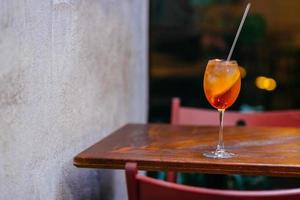 cocktail de spiritueux aperol frais, sur table en bois au restaurant. coup horizontal de boisson d'été. liquide orange avec de la glace. boisson apéritive. photo