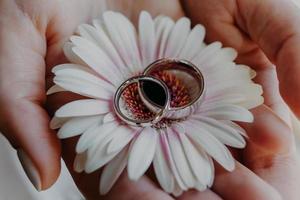 anneaux de mariage en argent contre la fleur sur les mains de la femme. photo en gros plan. symbole du mariage. bijoux. concept d'amour et de romance.