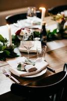 table de dîner élégante servie pour une occasion spéciale. table servie avec verres, assiette, boissons, fourchettes et couteaux, bougies allumées. table de fête servie prête pour les invités. table de mariage de luxe photo