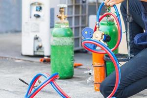 homme de réparation de climatisation tenant un manomètre sur les gaz combustibles et le réservoir d'oxygène pour souder ou couper des métaux, des procédés de soudage oxy-combustible et de coupage oxy-combustible photo