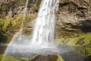 bel arc-en-ciel à seljalandsfoss découlant de la montagne dans la rivière photo