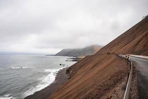 Avis de forte pente rocheuse brune à côté de la rocade par plage contre ciel nuageux photo