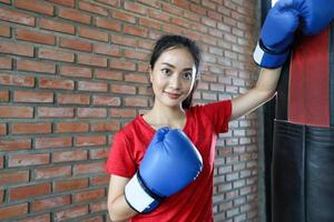 belles femmes boxeur asiatique heureux et amusant fitness boxe et poinçonnage d'un sac avec des gants de boxe. photo