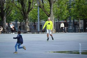 vilnius, lituanie. 06 juin 2022 - homme à roulettes en sweat-shirt adidas jaune vif s'entraînant sur la place lukiskiu au début de l'été près de la fontaine au sol photo