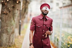 portrait d'un militaire afro-américain en uniforme rouge, sungalasses et béret. capitaine fume un cigare. photo