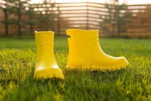 Des bottes jaunes se dressent sur une pelouse verte dans le jardin de printemps - concept de vie d'été et de campagne photo