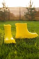 Des bottes jaunes se dressent sur une pelouse verte dans le jardin de printemps - concept de vie d'été et de campagne photo