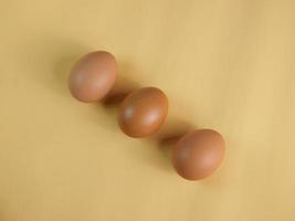 pondre trois œufs d'affilée, disposés en diagonale. tourné dans un studio avec lumière et ombres sur un fond de couleur coquille d'oeuf. photo