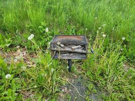 ancien barbecue avec cendres et mauvaises herbes vertes photo