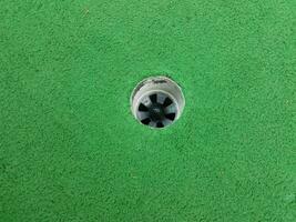 balle de golf noire dans le trou sur le parcours de golf miniature photo