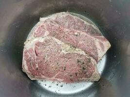 steak de boeuf avec assaisonnement et liquide dans une marmite en métal photo