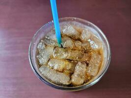 soda et glace dans un verre avec une paille bleue sur la table photo