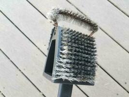 brosse métallique noire pour nettoyer la grille et le bois du barbecue photo