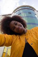 une femme afro-américaine heureuse et jeune prend un selfie, gros plan photo