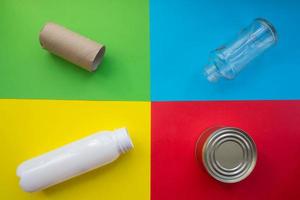 concept de recyclage tri des déchets. bouteille en verre, boîte en métal, bouteille en plastique et manchon de papier toilette sur fond coloré photo