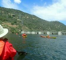 kayakiste en gilet orange avec chapeau en kayak sur rivière avec collines photo