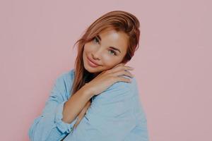 charmante jeune femme souriant agréablement à la caméra sur fond rose photo