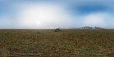 lever de soleil brumeux sur Prairie avec petit avion. panorama équirectangulaire complet à 360°. skybox en réalité virtuelle ou contenu graphique 3d comme arrière-plan photoréaliste. photo