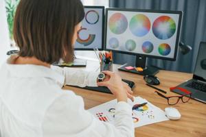 avec du papier. femme designer travaillant au bureau à l'aide d'un ordinateur photo