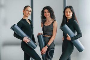 tenant des tapis de yoga. femmes en vêtements sportifs debout dans le centre de remise en forme photo