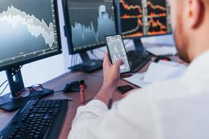 en utilisant le téléphone. négociant en bourse travaillant au bureau avec la technologie d'échange photo