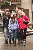 Famille adolescente marchant le long de la rue de la ville enneigée dans la station de ski
