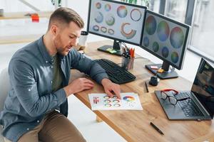 papier de différentes couleurs. designer masculin travaillant au bureau à l'aide d'un ordinateur photo