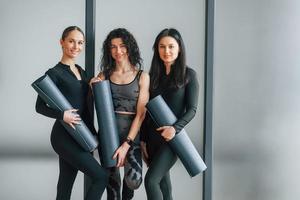 tenant des tapis de yoga. femmes en vêtements sportifs debout dans le centre de remise en forme photo