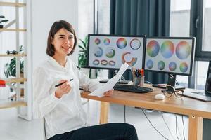 avec du papier. femme designer travaillant au bureau à l'aide d'un ordinateur photo