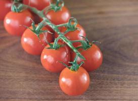 délicieuses tomates cerises sur une tige sur une surface en bois. photo