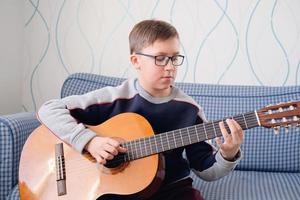 apprendre à jouer de la guitare. éducation musicale. garçon jouant de la guitare acoustique. photo