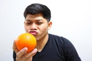 homme asiatique séduisant mangeant des oranges. isolé sur fond blanc photo