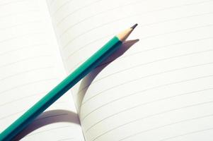 crayon bleu aqua sur un cahier ouvert. image en gros plan d'un crayon sur du papier blanc. photo