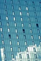 ciel bleu et nuages réfléchis sur la façade du bâtiment en miroir moderne. photo