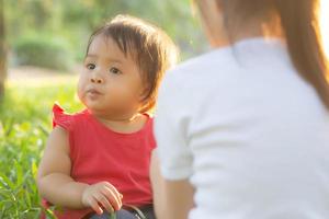 beau jeune enfant asiatique assis jouant en été dans le parc avec plaisir et gai sur l'herbe verte, activité des enfants avec détente et bonheur ensemble sur le pré, la famille et le concept de vacances. photo